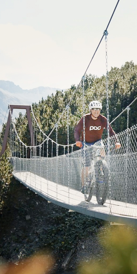 Martin Vincenz fährt über eine Hängebrücke im Welschtobel bei Arosa