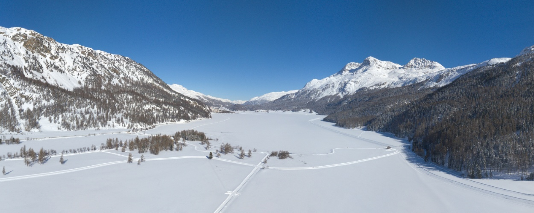Blick von Oben auf einen Teil der Rundloipe und den gefrorenen Silvaplanasee