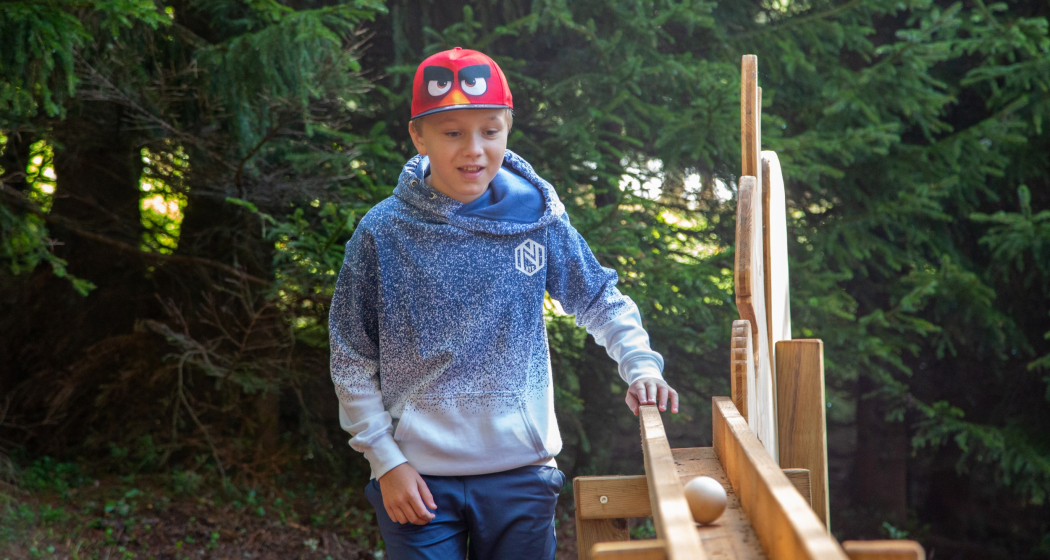 Das Foto zeigt einen Jungen der nach seinem Ball in der Bahn schaut Das Foto zeigt einen Jungen der nach seinem Ball in der Bahn schaut