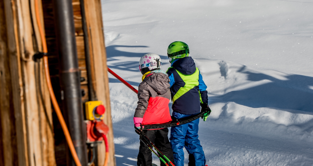 Das Foto zeigt zwei junge Kinder die auf dem Skilift Parli eingestiegen sind