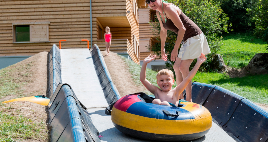 Das Foto zeigt eine Mutter die ihr Kind der Tubingbahn runter schiebt
