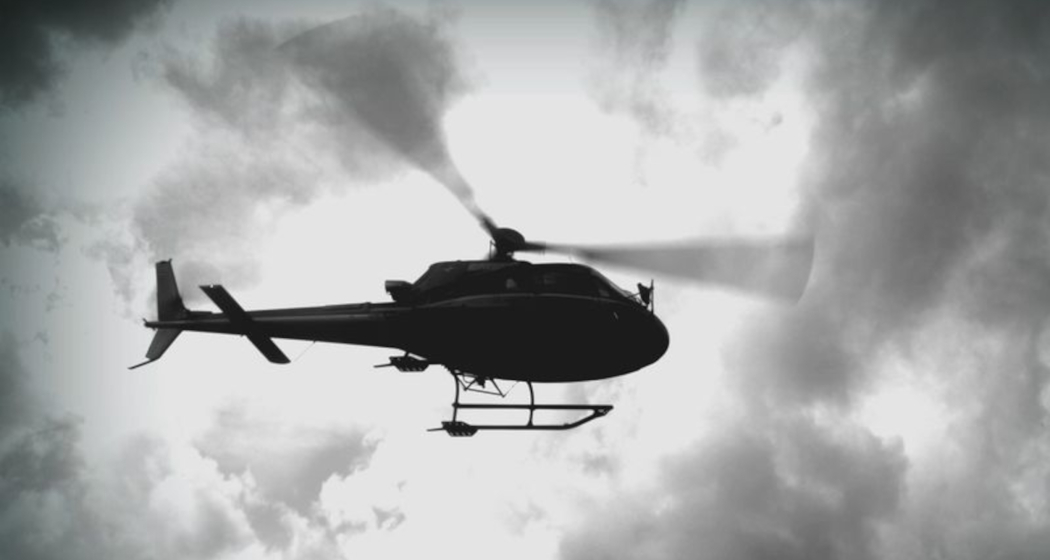 Das Foto zeigt ein Helikopter von unten der nah am Boden vorbeifliegt