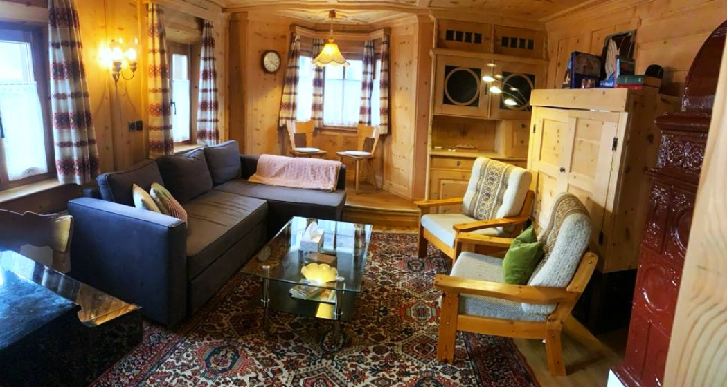 Alte Arvenstube mit Sofa, Sesseln, Büchern und TV