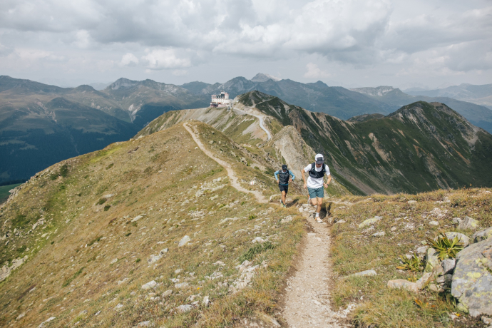 zwei Trailrunners laufen den Grat entlang. Im Hintergrund: das Jakobshorn