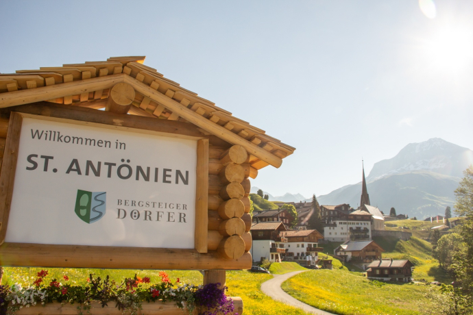 Panneau local du village d'alpinistes de St. Antönien, en arrière-plan le village Panneau local du village d'alpinistes de St. Antönien, en arrière-plan le village