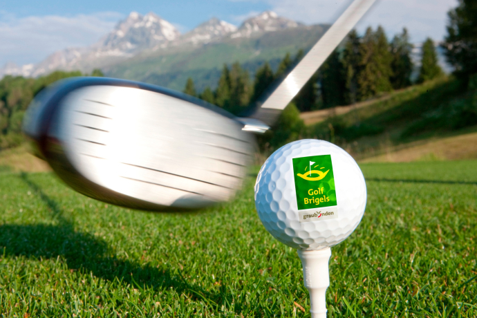 Das Foto zeigt einen Golfschläger der kurz davor steht einen Golfball zu schießen