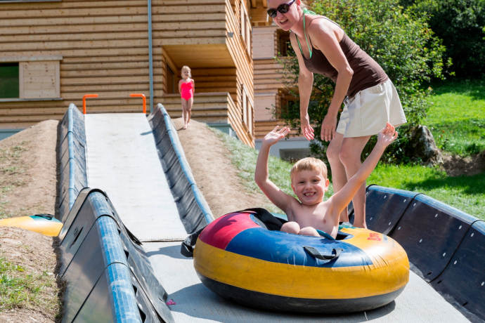 Das Foto zeigt eine Mutter die ihr Kind der Tubingbahn runter schiebt