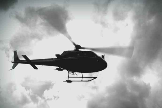 Das Foto zeigt ein Helikopter von unten der nah am Boden vorbeifliegt