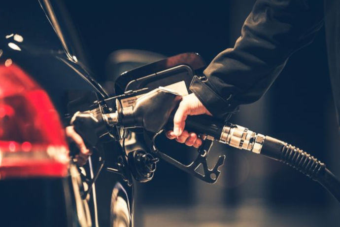 Das Foto zeigt eine person die ihr Auto mit Benzin tankt