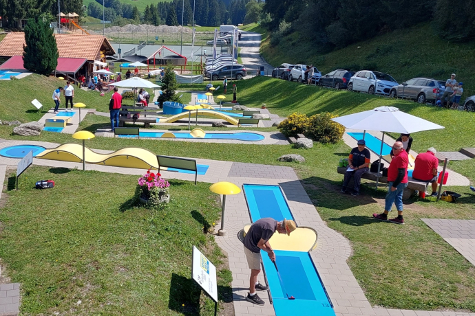 Das Foto zeigt die Minigolfanlage mit vielen Besuchern.