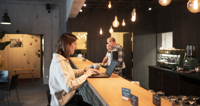 Flexibles Arbeiten in der STORY Thusis (Foto: © Graubünden Ferien / Marco Hartmann) Eine Frau arbeitet an Ihrem Laptop an der Bar der STORY Thusis