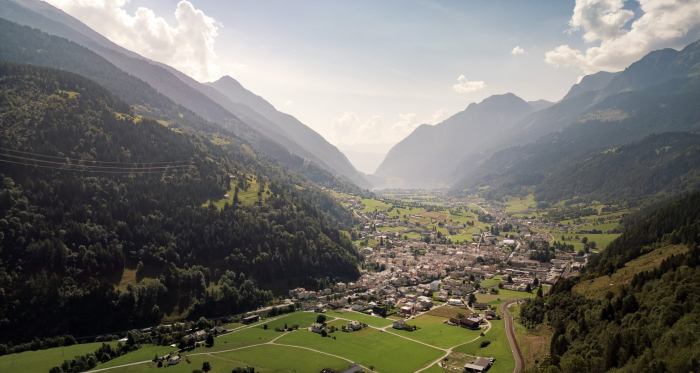 Poschiavo eingebettet in die Alpen – ein Bergdorf mit Blick auf den Lago di Poschiavo und einer malerischen Umgebung (Foto: © Marco Hartmann) Luftaufnahme von Poschiavo mit umliegender Landschaft und dem Lago di Poschiavo im Hintergrund