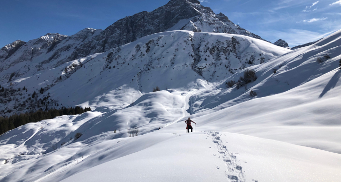 Winterwunderland für Schneeschuhtouren (Foto: © Seraina von Planta) Eine Person wandert mit Schneeschuhen durch tiefen Schnee vor Bergkulisse