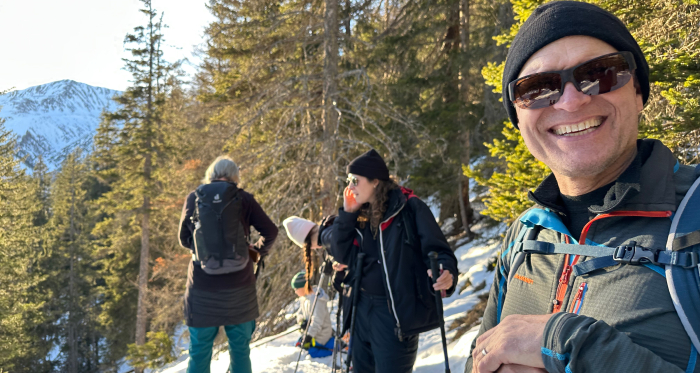 Gemeinsam unterwegs auf einer sonnigen Schneeschuhtour durch verschneite Wälder Schneeschuhwandergruppe mit Wanderleiter Marc Steiner im Wald