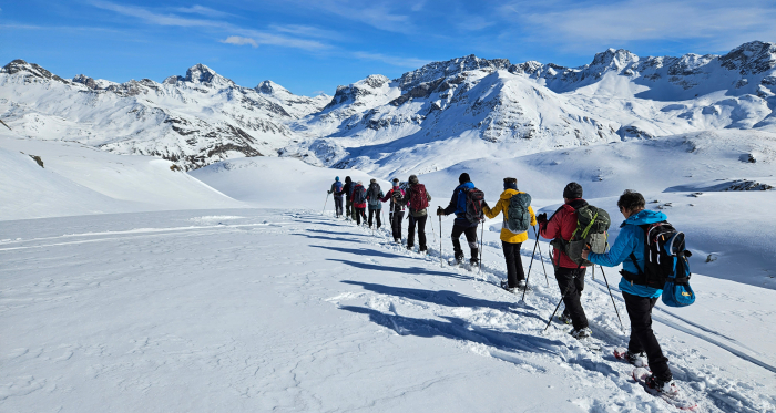 Schneeschuhwandergruppe vor verschneiter Bergkulisse