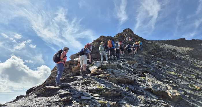 Wandergruppe auf steilem Pfad im alpinen Gelände bei sonnigem Wetter