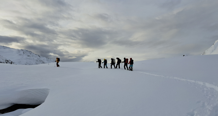 Schneeschuhwanderung mit Anita Panzer in einer verschneiten Winterlandschaft Wandergruppe mit Schneeschuhen bei bewölktem Himmel unterwegs im Tiefschnee