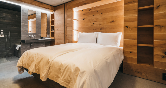 Übernachten im stilvollen rocksresort in Laax (Foto: © LAAX / Weisse Arena Gruppe) Modernes Doppelzimmer im rocksresort**** in Laax mit Holzwänden und offener Dusche