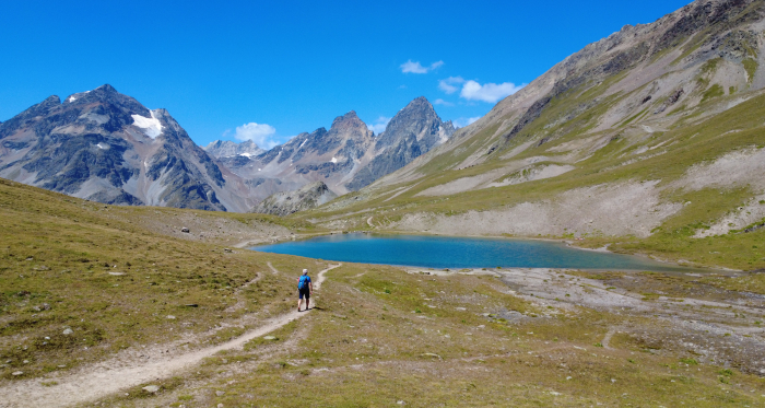 Wanderer auf einem Pfad am Ufer des Lai Blau, umgeben von felsigen Gipfeln