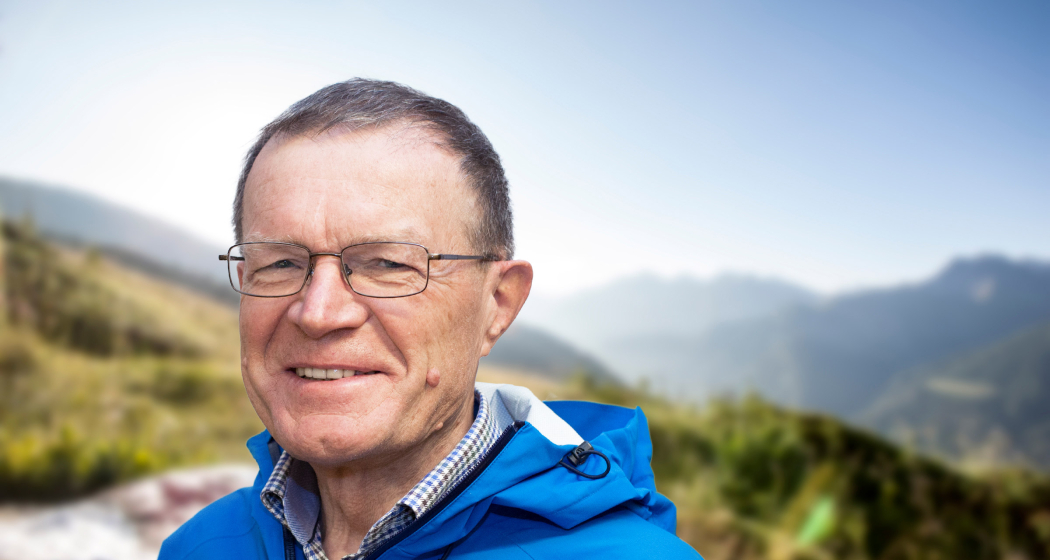 Porträt von Wanderleiter Ruedi Zuber mit Bergen im Hintergrund