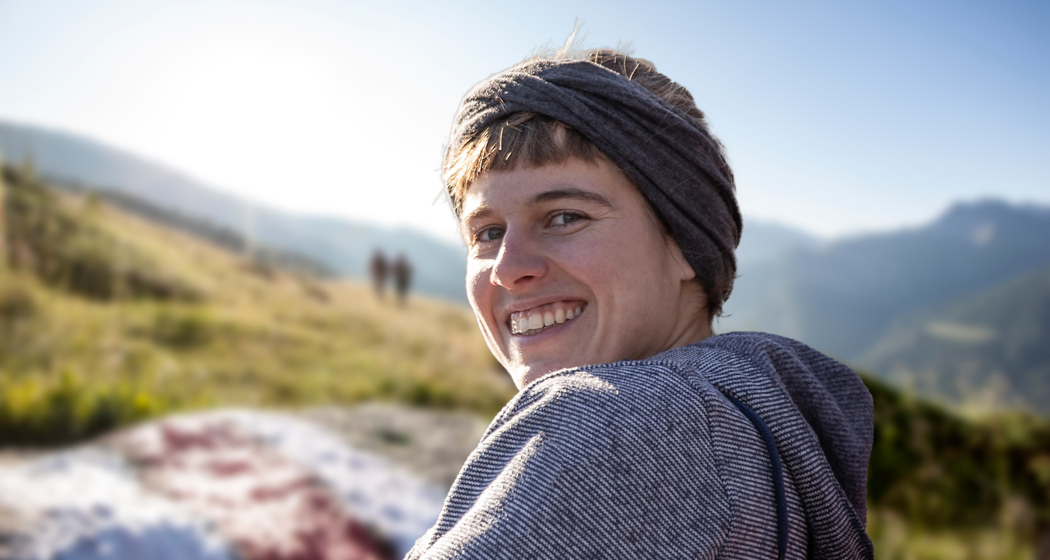 Wanderleiterin Fabienne Kaufmann – unterwegs mit Herz, Wissen und Blick für die besonderen Momente in der Natur Porträt der Wanderleiterin Fabienne Kaufmann mit Blick in die Kamera, im Hintergrund eine sommerliche Berglandschaft