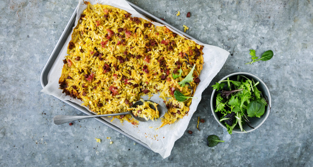 Plain in Pigna – der herzhafte Kartoffelauflauf mit Rohschinken und Wurst wird traditionell im Ofen gebacken und ist ein Klassiker der Bündner Küche (Bildquelle: kartoffel.ch) Bündner Spezialität Plain in Pigna auf einem Blech mit frischem Blattsalat