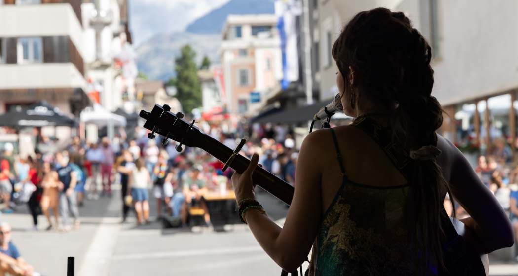 Eine Frau ist auf der Bühne und hat eine Gitarre in der Hand und singt.