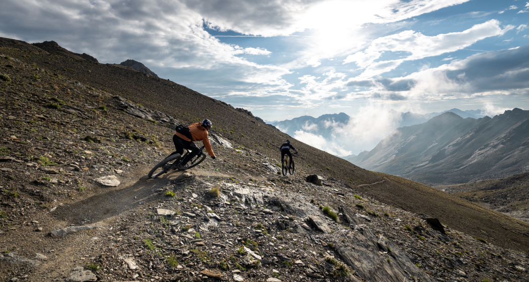 Zwei Mountainbiker auf einem steinigen Trail in den Bündner Bergen