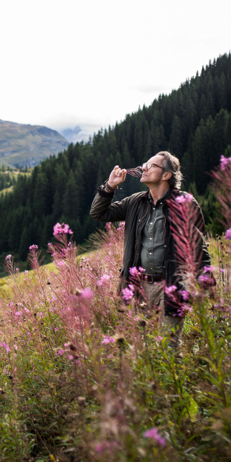 Bergluft-Sommelier Patrick Stebler riecht an einer Blume in Vals