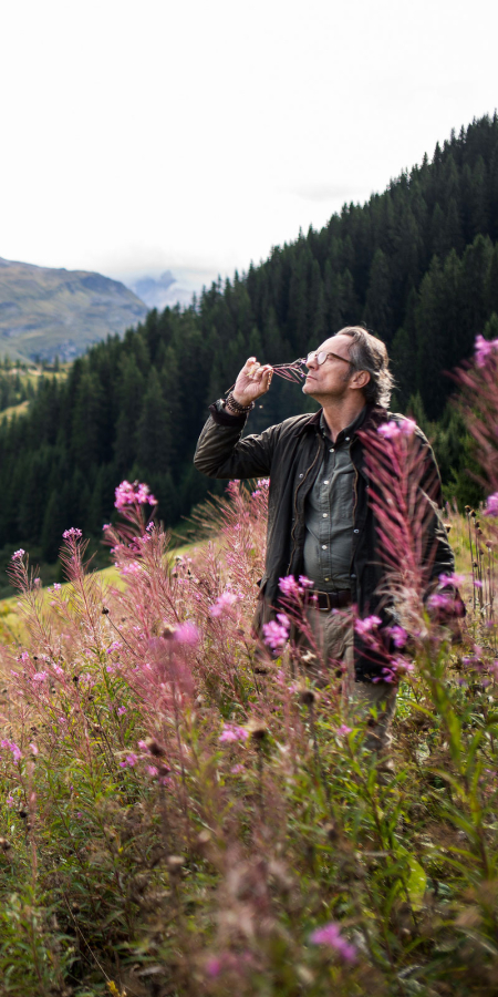 Bergluft-Sommelier Patrick Stebler in Vals (Foto: © Marco Hartmann, Graubünden Ferien) Bergluft-Sommelier Patrick Stebler riecht an einer Blume in Vals
