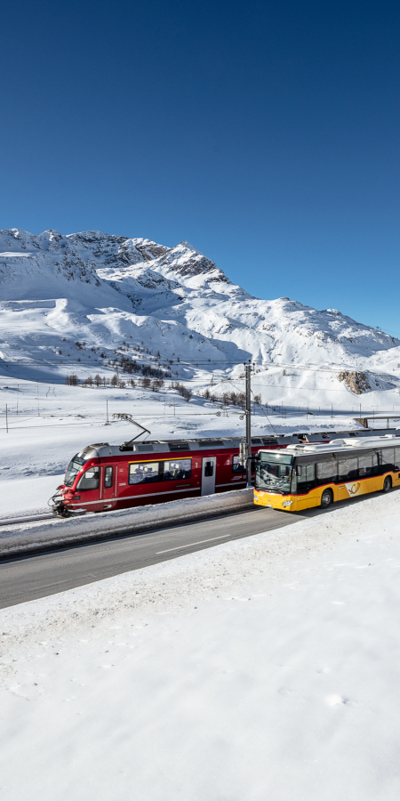 Ein Postauto und ein Zug der Rhätischen Bahn auf dem Berninapass