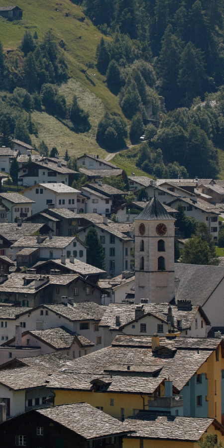 Summer day in the mountain village of Vals with views of traditional architecture and green hills (Photo: © 7132 Hotel / Julien Balmer) Mountain village of Vals in summer with green meadows and typical stone roofs