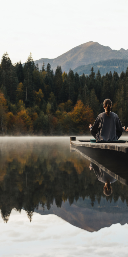 Zwei Frauen machen Yoga an einem Bergsee.