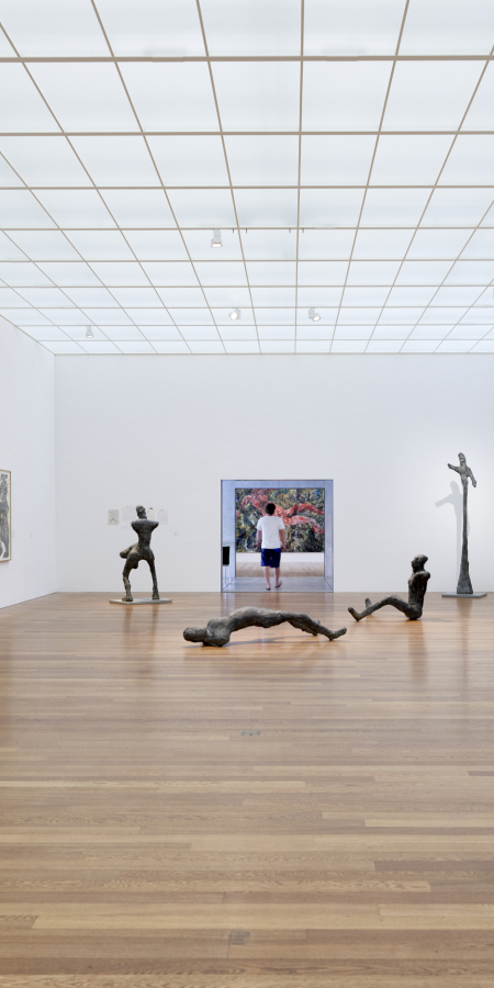 Una grande e luminosa sala espositiva del Kirchner Museum di Davos con pavimento in legno, dipinti alle pareti e sculture di Ernst Ludwig Kirchner