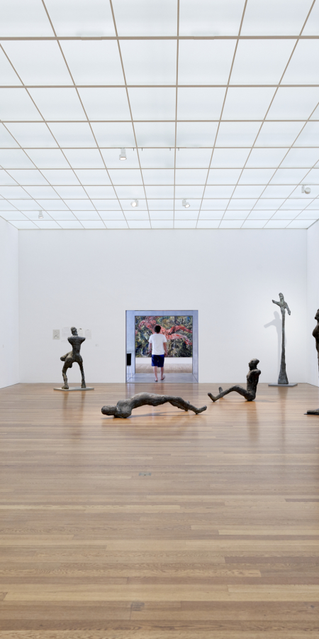 Una grande e luminosa sala espositiva del Kirchner Museum di Davos con pavimento in legno, dipinti alle pareti e sculture di Ernst Ludwig Kirchner