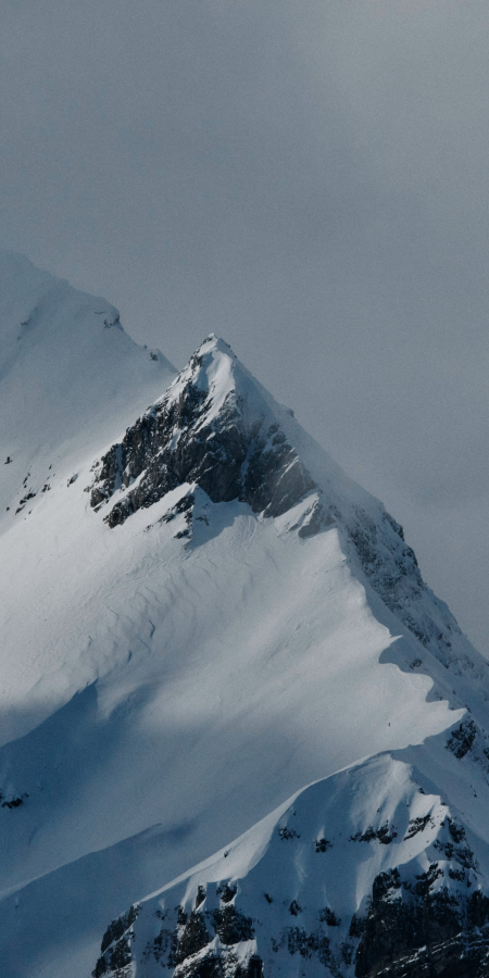 A snow-covered mountain peak surrounded by clouds