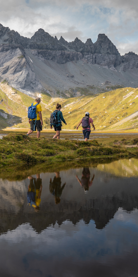 Wanderer auf dem Segnesboden, im Hintergrund die Tschingelhörner und deren Spiegelung im Wasser