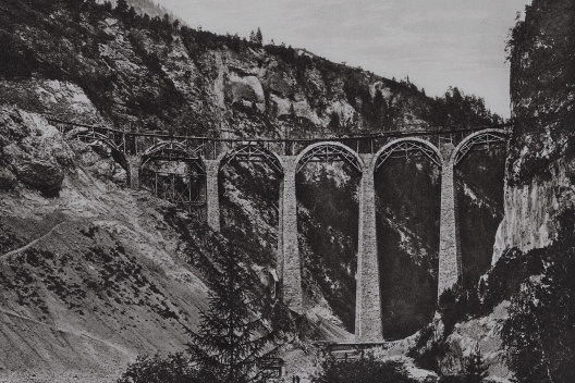 Die steinernen Rundbögen wurden mit Holzlehrgerüsten aufgebaut, die sich auf die Eisenträger an den Pfeilerköpfen stützten Fortgeschrittener Bau des Landwasserviadukts mit Rundbögen auf hölzernen Lehrgerüsten