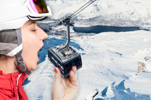 Eine übergrosse Skifahrerin in voller Montur beisst spielerisch in eine Gondel einer Bergbahn