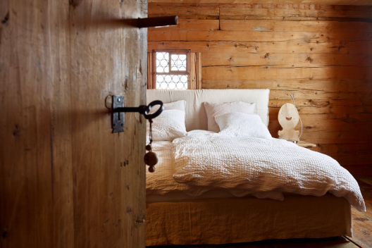 Blick durch die halboffene Holztür eines Gästezimmers mit Doppelbett im Nühus B&B