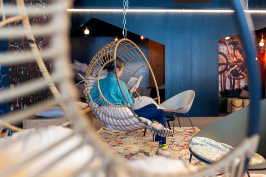 Eine Person liest ein Buch in einem Hängesessel in einer modernen Hotel-Lobby