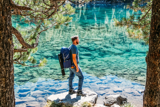 Pausing at Lagh da Saoseo – the crystal-clear water makes this lake one of the most photogenic spots in the region (Photo: © Christiane Setz-Müller & Moritz Müller) Hiker with backpack on the shore of Lagh da Saoseo with clear, turquoise water