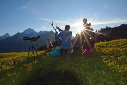 Wildtierbeobachtungen sind ein Erlebnis für Gross und Klein (Foto: © Tourismus Savognin Bivio Albula AG) Ein Wildtierexpertin zeigt Kindern auf einer Bergwiese ein Hirschgeweih