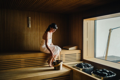 Sauna im Hotel Schweizerhof Lenzerheide (Foto: © Sandra Marusic) Eine Frau holt Wasser aus einem Kessel in einer Sauna im Hotel Schweizerhof Lenzerheide