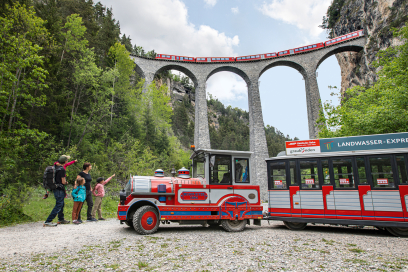 Mit dem Landwasser-Express gelangen Gäste bequem zum weltberühmten Viadukt – inklusive bester Aussicht auf vorbeifahrende Züge (Foto: © Rhätische Bahn / Manuel Rupp) Landwasser-Express mit Familie vor dem Landwasserviadukt in Graubünden