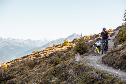 Zwei Personen fahren mit Mountainbikes auf einem schmalen Bergpfad.