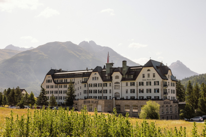 Historisches Grand Hotel Cresta Palace in Celerina, umgeben von einer Wiese und der imposanten Bergkulisse des Engadins.