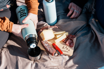 Rast im Schnee mit einer Thermoflasche und Bündner Spezialitäten auf einem Holzbrettli