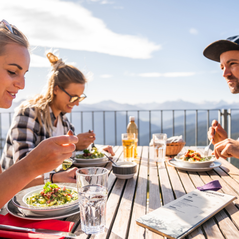 Wander*innen geniessen Mahlzeit und Aussicht in Flims (Foto: © Flims Laax Falera) Wander*innen geniessen Mahlzeit und Aussicht in Flims