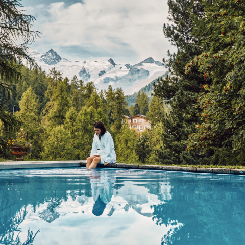 Entspannen mit Aussicht – der Aussenpool des Hotel Saratz in Pontresina bietet Ruhe und Gletscherblick gleichermassen (Foto: © Schweiz Tourismus / Colin Frei) Frau im Bademantel am Aussenpool des Hotel Saratz mit Blick auf Gletscher und Piz Glüschaint